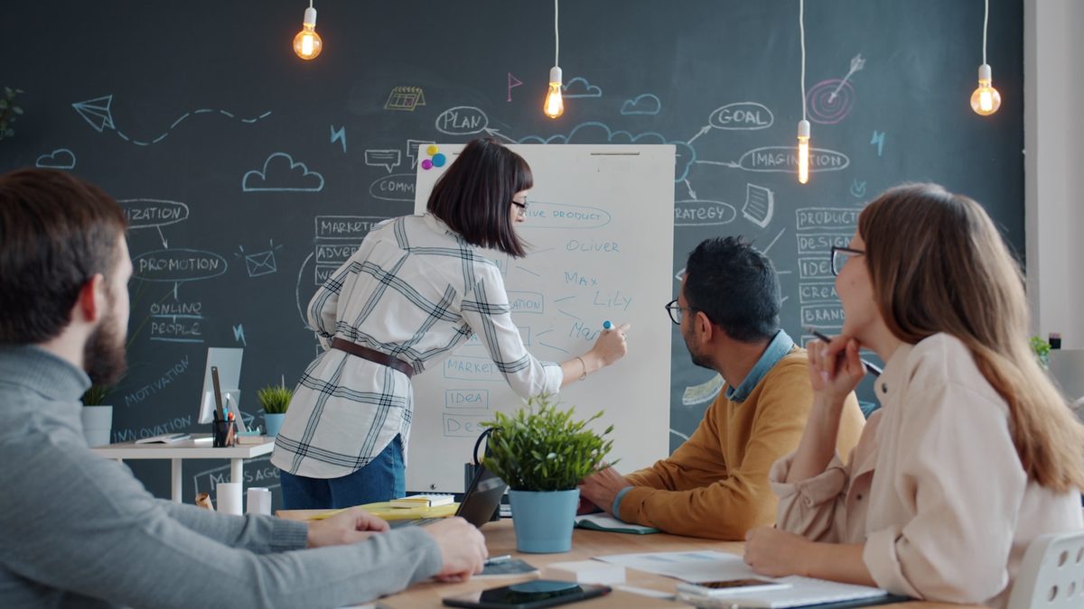 Équipe collaborant autour d'un tableau blanc dans un bureau lumineux