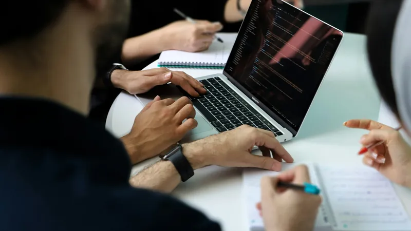Équipe en petit groupe réunie autour d'un ordinateur portable pour une session de travail