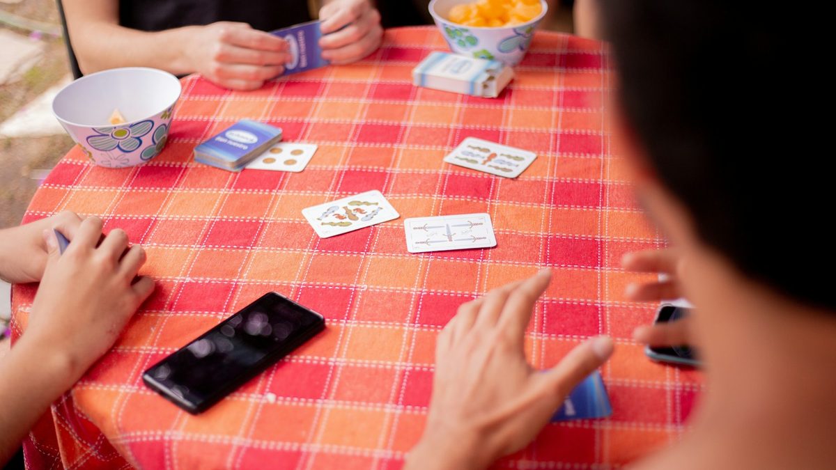 Des personnes jouent a un jeu de cartes autour d'une table — apprentissage par le jeu