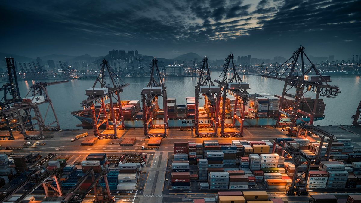 Terminal portuaire de nuit à Hong Kong : une rangée de portiques chargent des porte-conteneurs, image d'un cluster de nœuds exploité ensemble