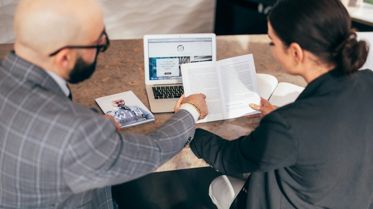 Un conseiller et une cliente étudient des documents et un ordinateur portable autour d'une table.